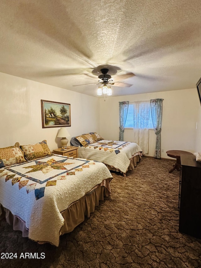 bedroom featuring ceiling fan, a textured ceiling, and dark colored carpet