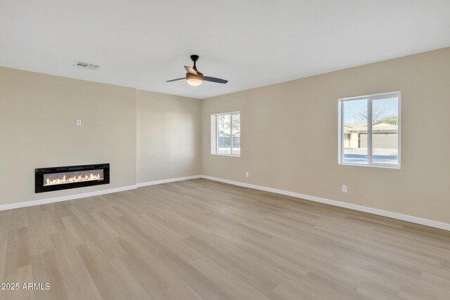 7607 N 42nd Ln, Phoenix, AZ 85051 - unfurnished living room with light wood-style floors, a glass covered fireplace, baseboards, and ceiling fan