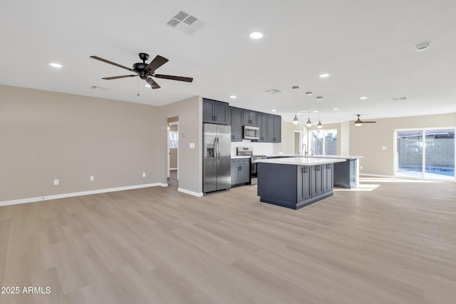 7607 N 42nd Ln, Phoenix, AZ 85051 - kitchen with appliances with stainless steel finishes, ceiling fan, open floor plan, a center island with sink, and light countertops