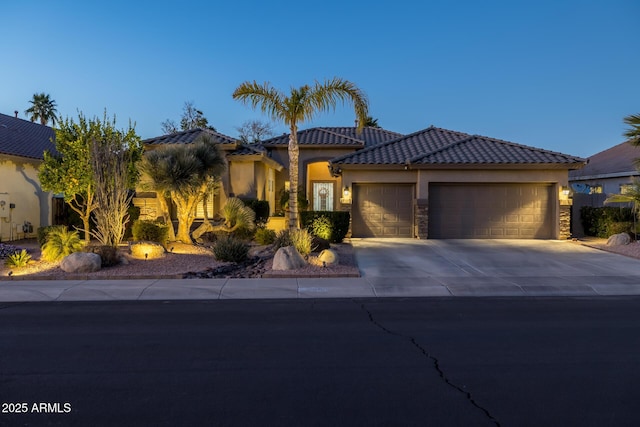 view of front of property with driveway, a garage, stone siding, a tile roof, and stucco siding