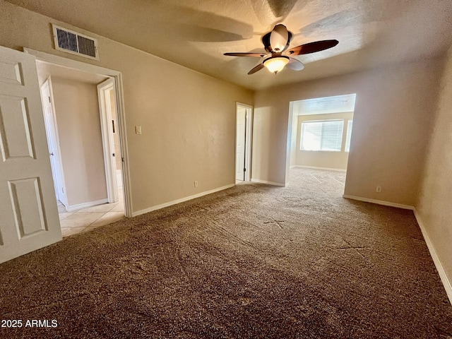 carpeted spare room featuring ceiling fan, visible vents, and baseboards