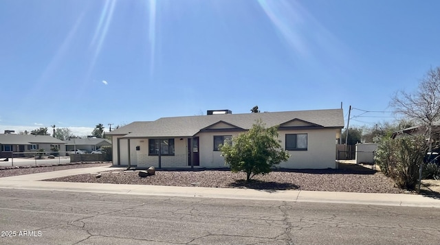 single story home featuring concrete driveway, brick siding, and fence