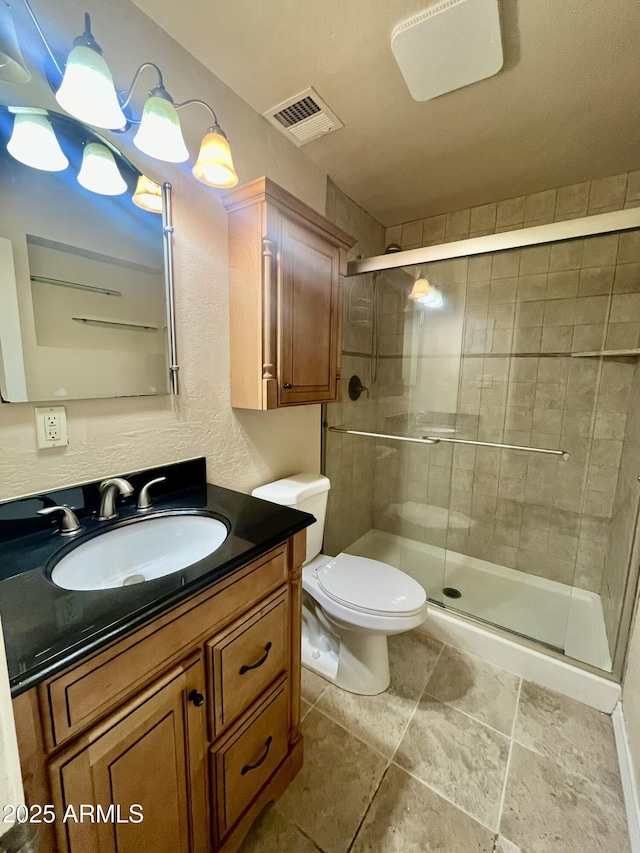 bathroom featuring toilet, a stall shower, visible vents, and vanity