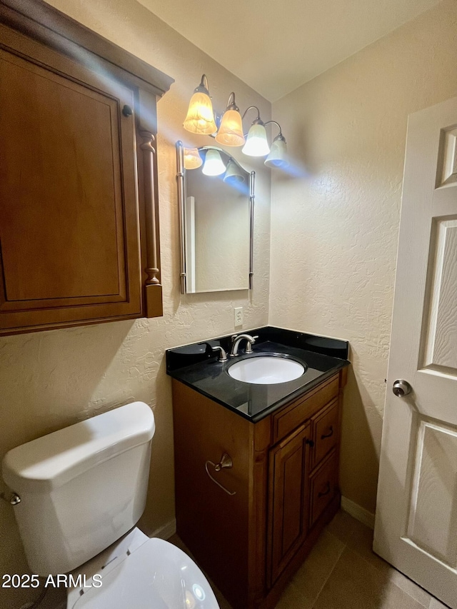 bathroom with a textured wall, vanity, and toilet