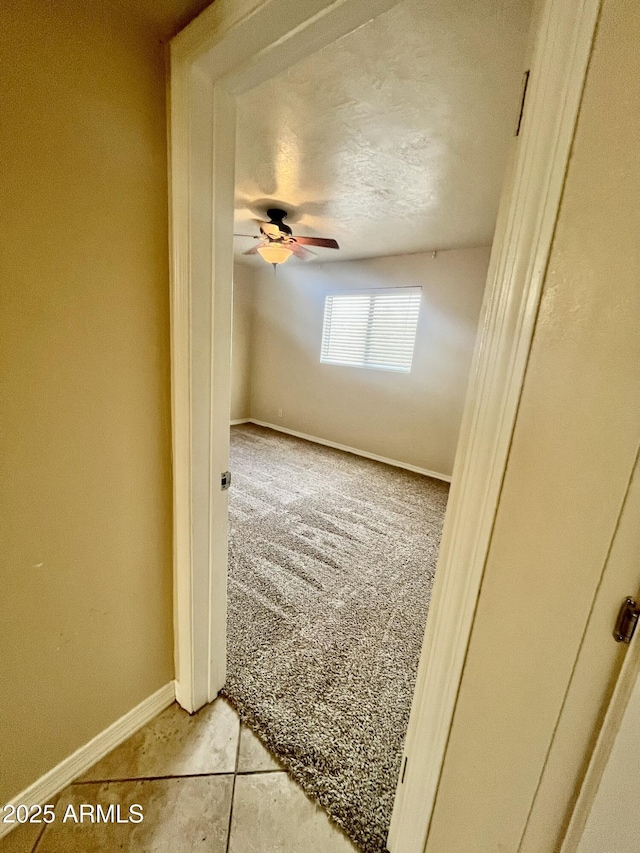 unfurnished room featuring ceiling fan, baseboards, and light colored carpet