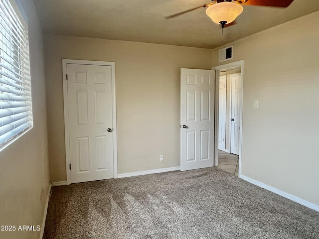 unfurnished bedroom with carpet flooring, visible vents, and baseboards