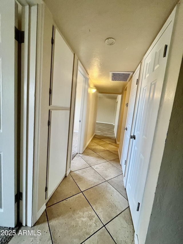 hall featuring light tile patterned floors and visible vents