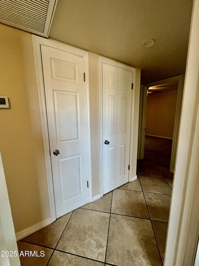 hall featuring visible vents, baseboards, and tile patterned floors