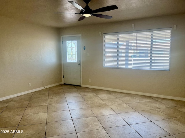 entryway featuring ceiling fan, a textured ceiling, light tile patterned flooring, and baseboards