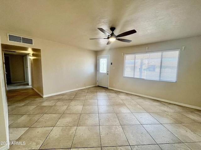 interior space with light tile patterned floors, a textured ceiling, a ceiling fan, visible vents, and baseboards