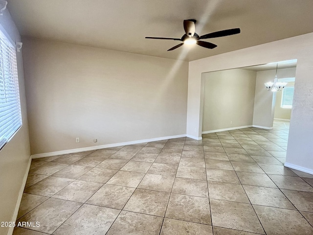 spare room featuring light tile patterned flooring, baseboards, and ceiling fan with notable chandelier