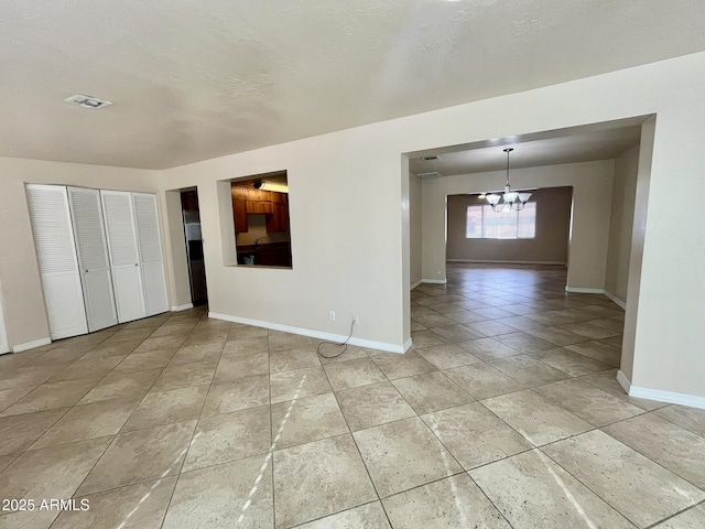 unfurnished room with baseboards, visible vents, a notable chandelier, and light tile patterned flooring