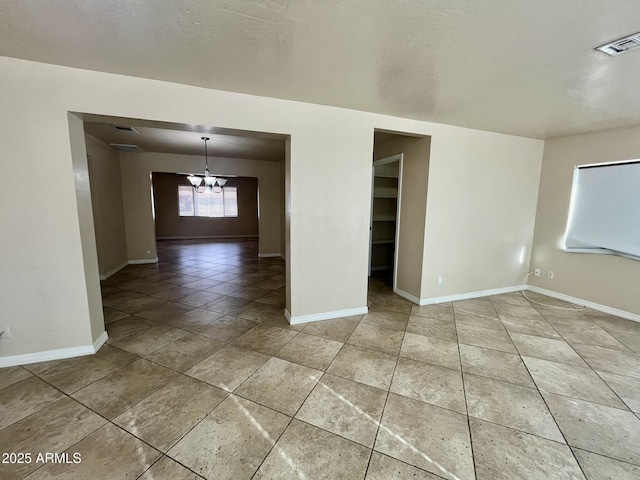 spare room featuring light tile patterned floors, visible vents, baseboards, and an inviting chandelier