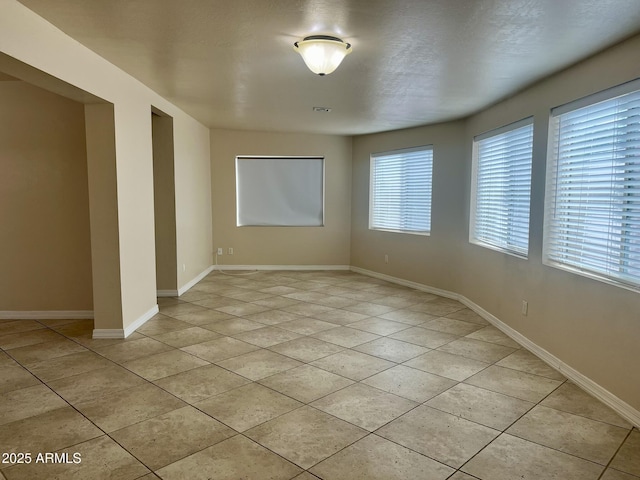 unfurnished room featuring light tile patterned floors and baseboards