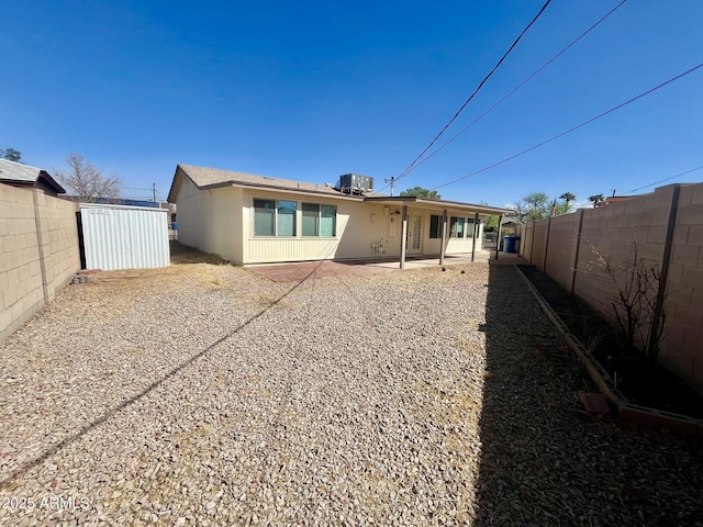 rear view of property with a fenced backyard, central AC, and a patio