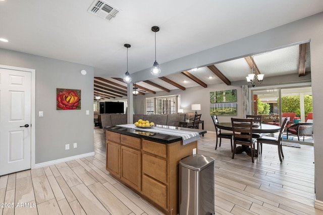 kitchen featuring vaulted ceiling with beams, decorative light fixtures, ceiling fan with notable chandelier, and a center island