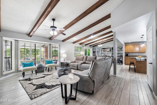 living room with ceiling fan with notable chandelier, light hardwood / wood-style flooring, lofted ceiling with beams, and a textured ceiling