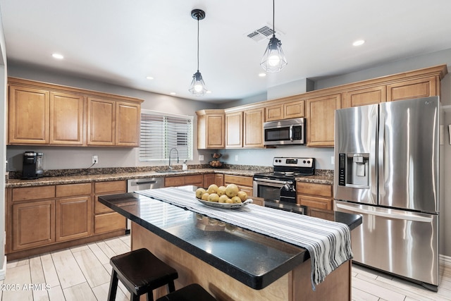 kitchen with sink, a center island, appliances with stainless steel finishes, a kitchen breakfast bar, and pendant lighting