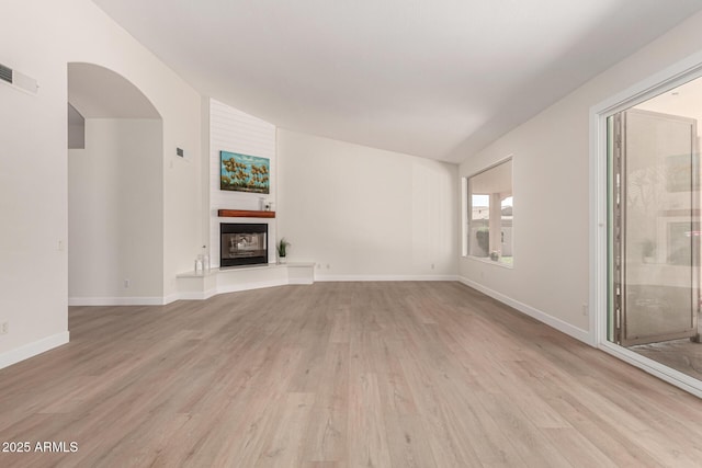 4010 N 156th Ln, Goodyear, AZ 85395 - unfurnished living room with a fireplace, light wood-type flooring, visible vents, lofted ceiling, and baseboards