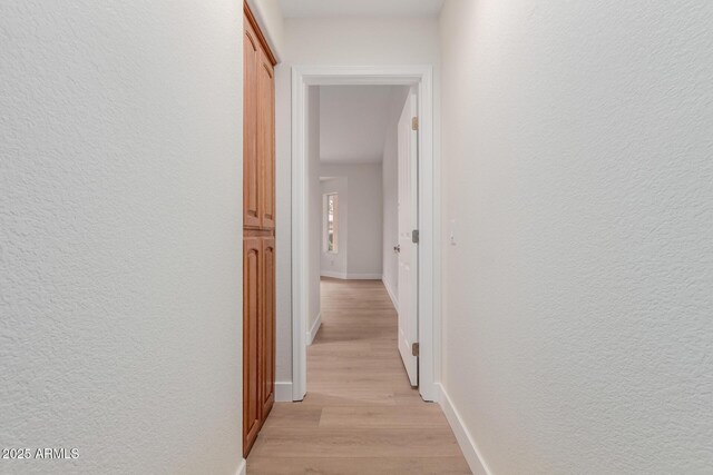 4010 N 156th Ln, Goodyear, AZ 85395 - hallway with light wood-style flooring, a textured wall, and baseboards