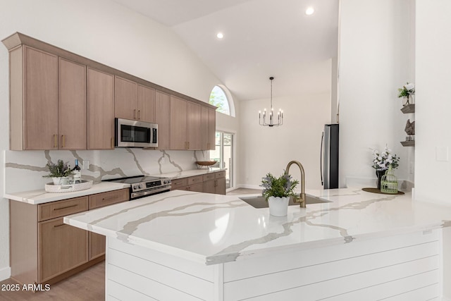 4010 N 156th Ln, Goodyear, AZ 85395 - kitchen featuring a peninsula, appliances with stainless steel finishes, light stone counters, a sink, and lofted ceiling