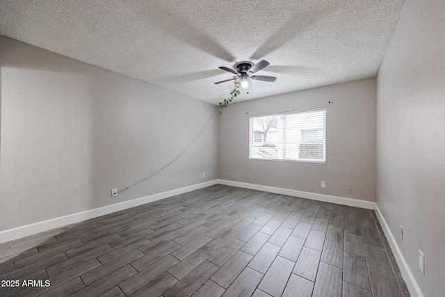 spare room with dark wood finished floors, a textured ceiling, baseboards, and a ceiling fan