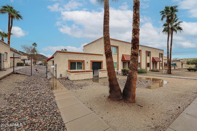 view of front facade with stucco siding, fence, and a gate