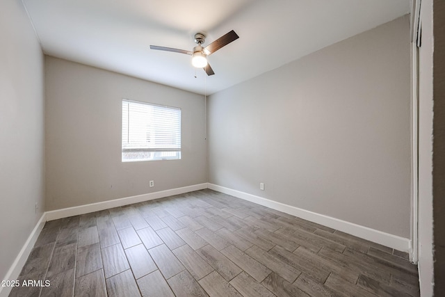 empty room with dark wood-type flooring, a ceiling fan, and baseboards