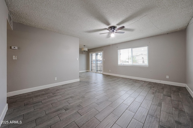 empty room with baseboards, a textured ceiling, dark wood-style floors, and a ceiling fan