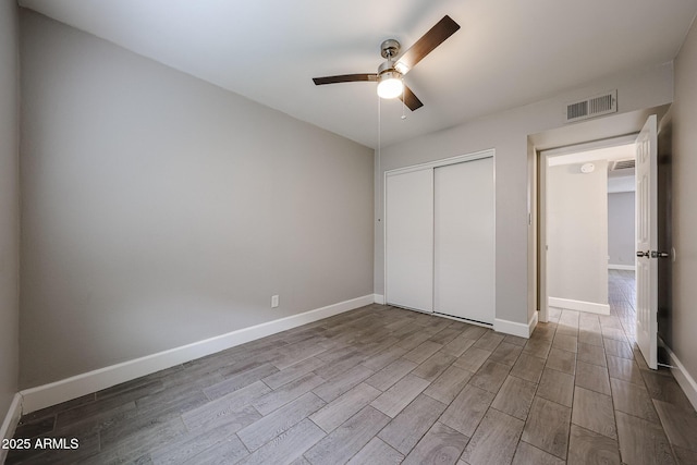 unfurnished bedroom featuring visible vents, wood finished floors, a closet, baseboards, and ceiling fan