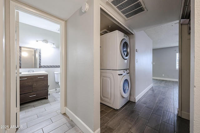 washroom featuring visible vents, stacked washing maching and dryer, baseboards, and wood tiled floor