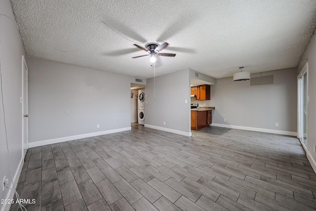 unfurnished living room featuring visible vents, baseboards, ceiling fan, dark wood finished floors, and washer / dryer