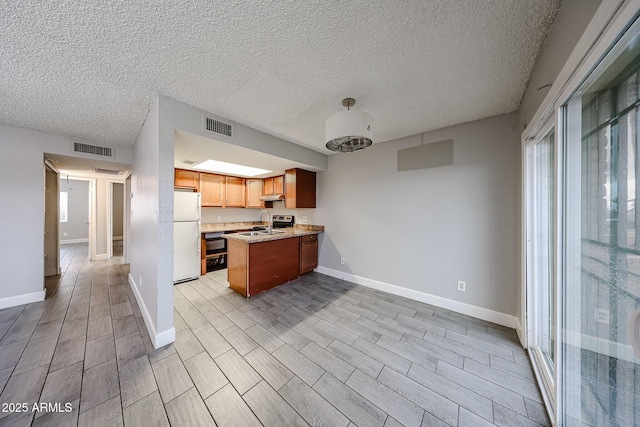 kitchen with visible vents, a sink, freestanding refrigerator, a peninsula, and light countertops