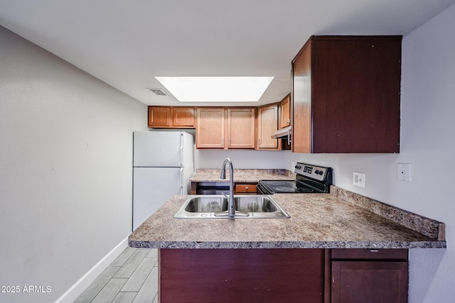 kitchen featuring a skylight, stainless steel electric stove, freestanding refrigerator, a sink, and under cabinet range hood