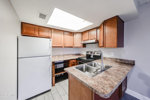 kitchen featuring under cabinet range hood, stainless steel range with electric stovetop, a peninsula, freestanding refrigerator, and a sink