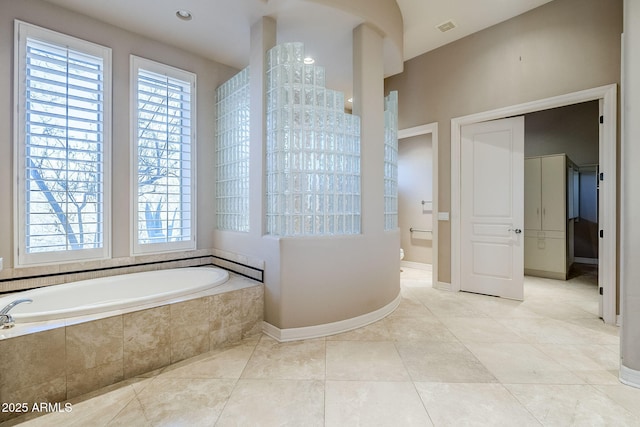 bathroom featuring a relaxing tiled tub and tile patterned floors