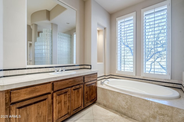 bathroom with tile patterned flooring, vanity, and tiled tub