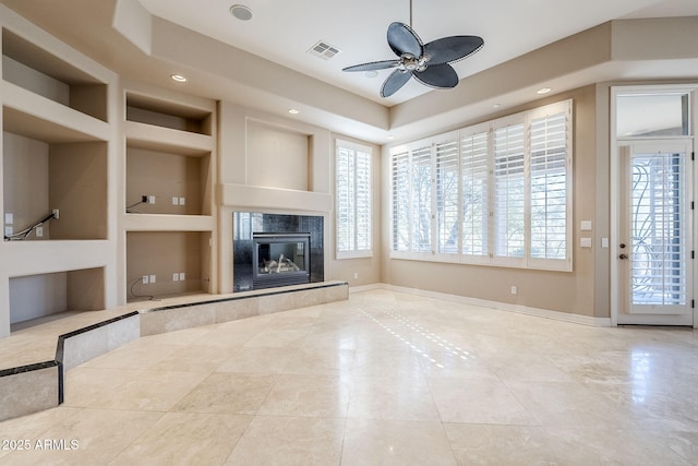 unfurnished living room with tile patterned flooring, ceiling fan, built in features, and a fireplace