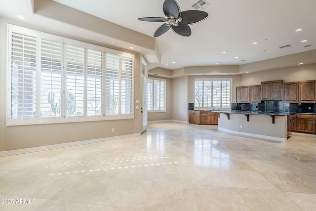 kitchen with decorative backsplash, a kitchen breakfast bar, ceiling fan, and a kitchen island