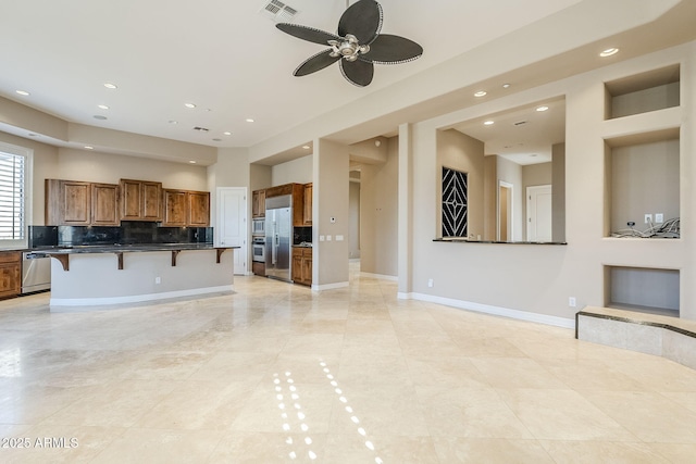 kitchen featuring a breakfast bar, ceiling fan, appliances with stainless steel finishes, tasteful backsplash, and a kitchen island