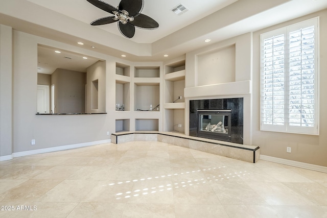 unfurnished living room with built in shelves, ceiling fan, a fireplace, and tile patterned flooring