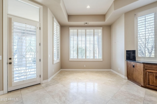 doorway to outside with light tile patterned flooring and a tray ceiling