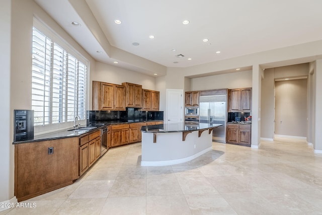 kitchen with a center island, built in appliances, a breakfast bar, and decorative backsplash