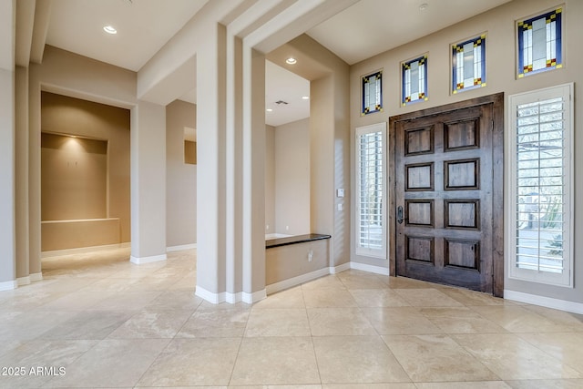 tiled entrance foyer with a towering ceiling and a wealth of natural light