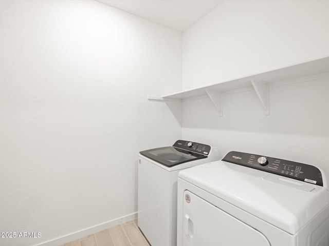 clothes washing area featuring laundry area, baseboards, light wood-style floors, and washer and dryer