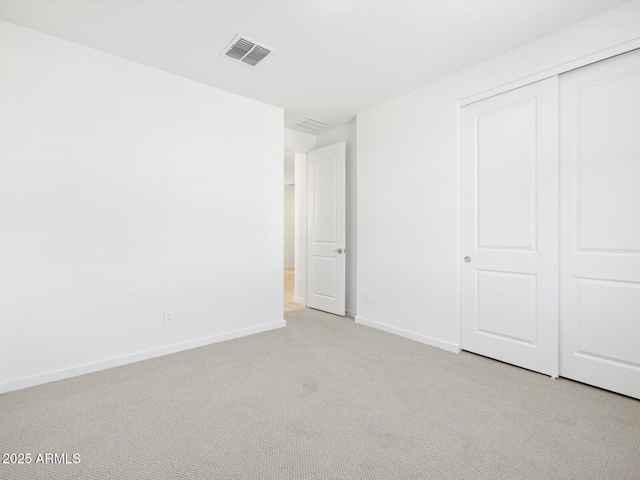 unfurnished bedroom featuring baseboards, visible vents, a closet, and light colored carpet