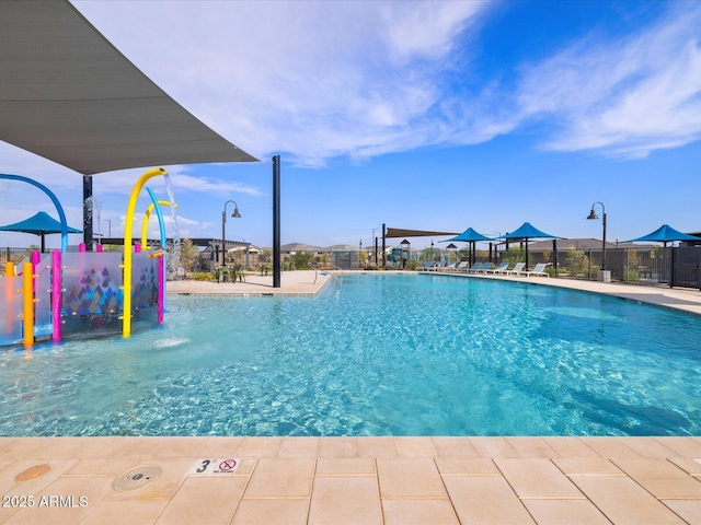 pool with a water play area, playground community, and fence