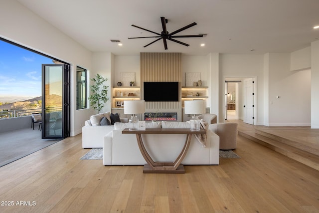 13631 E Windrose Dr, Scottsdale, AZ 85259 - living room with light wood-style floors, ceiling fan, a glass covered fireplace, recessed lighting, and baseboards