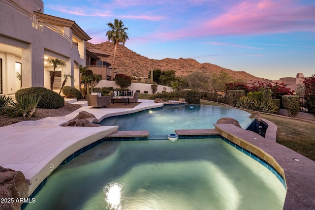 13631 E Windrose Dr, Scottsdale, AZ 85259 - pool at dusk with a pool with connected hot tub, outdoor lounge area, a mountain view, and a patio area