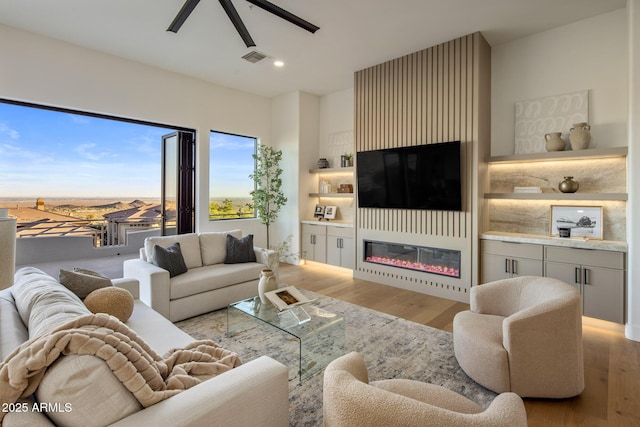 13631 E Windrose Dr, Scottsdale, AZ 85259 - living area with wood finished floors, a glass covered fireplace, ceiling fan, and recessed lighting